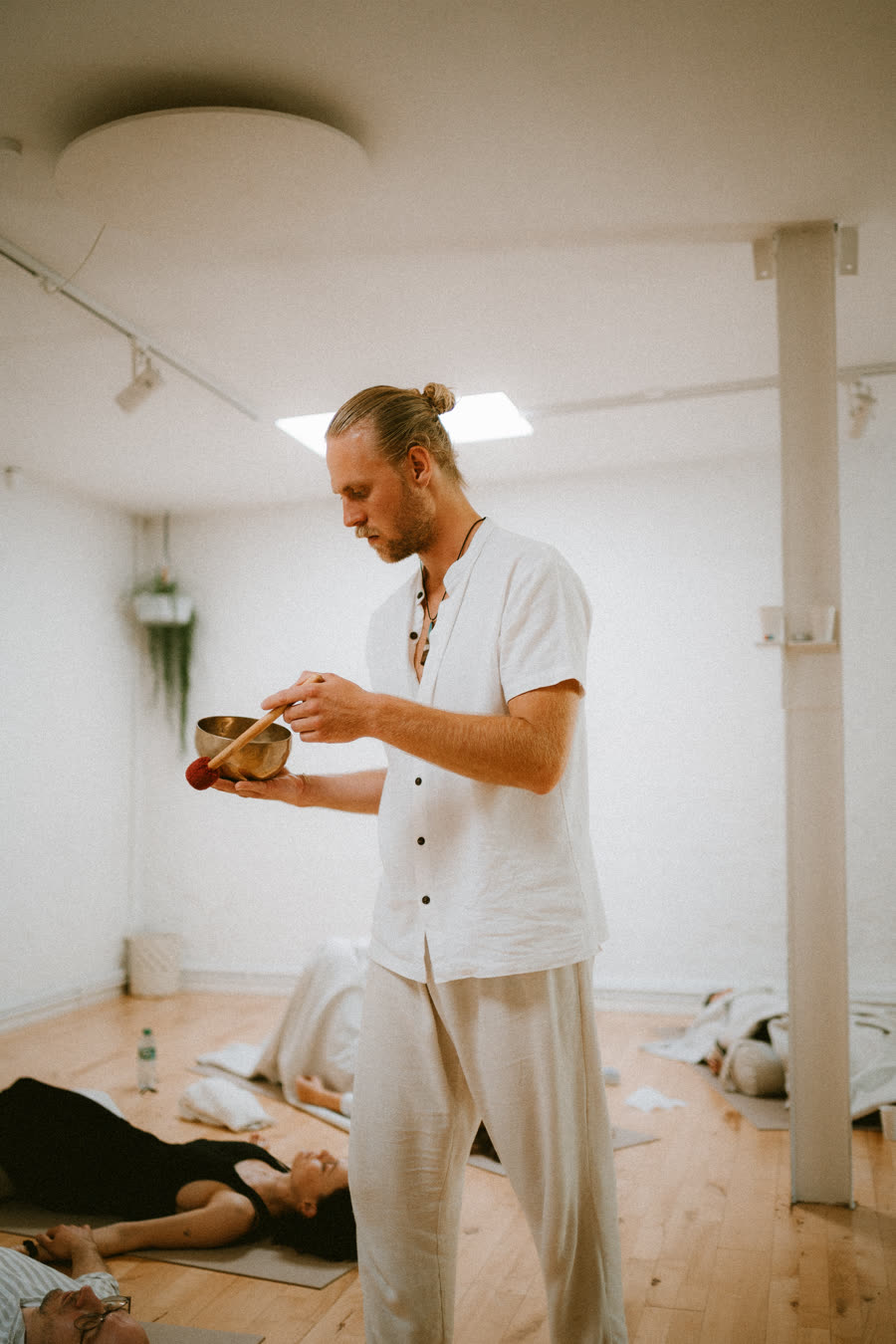Toby playing a singing bowl over a room of people lying down