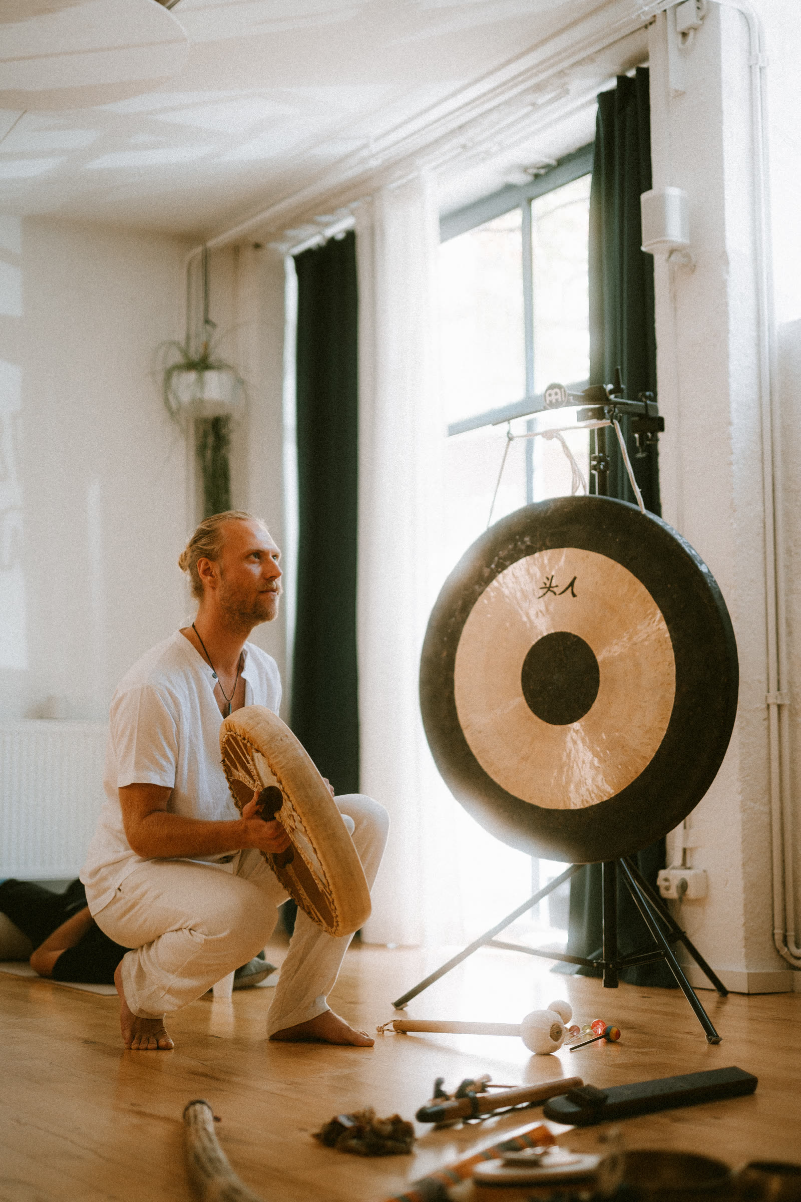 Toby playing a frame drum beside the gong in the studio